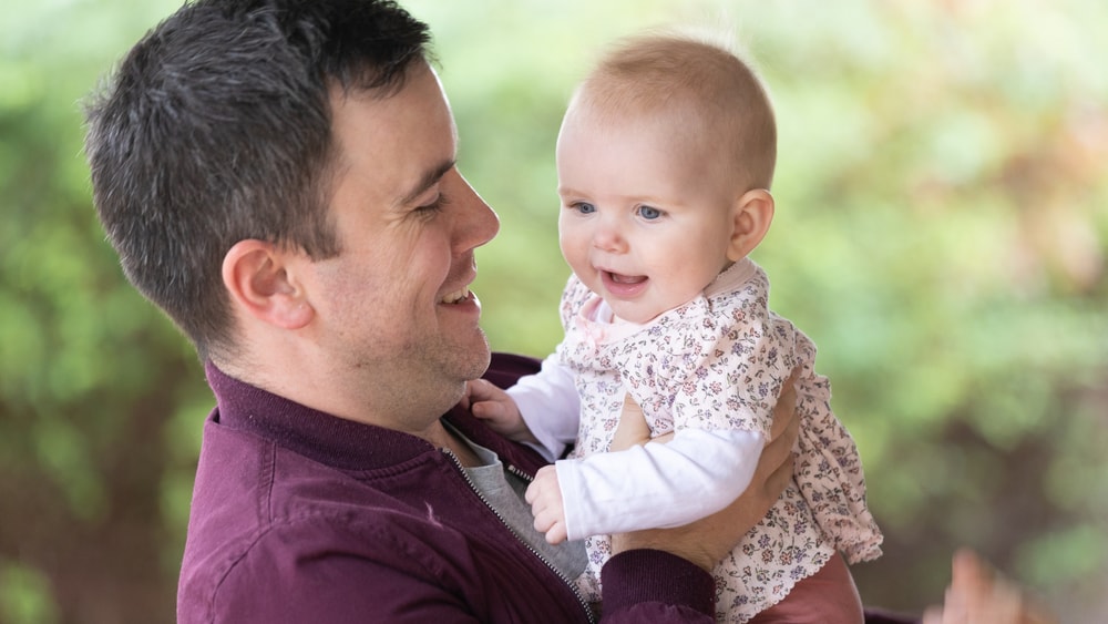 Parent holding baby and smiling.