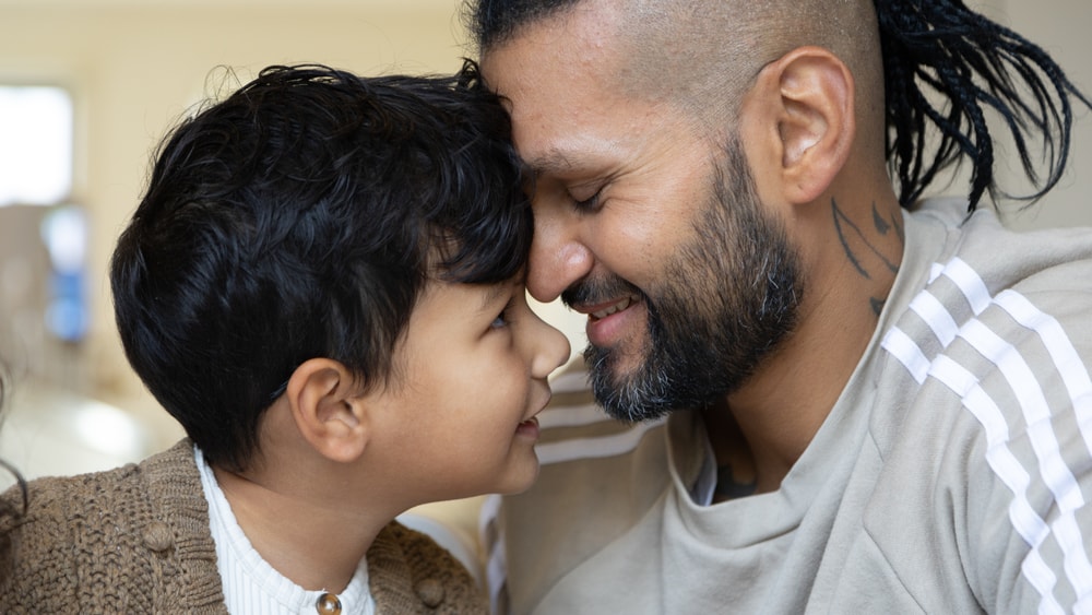 Dad and child looking at each other and smiling.