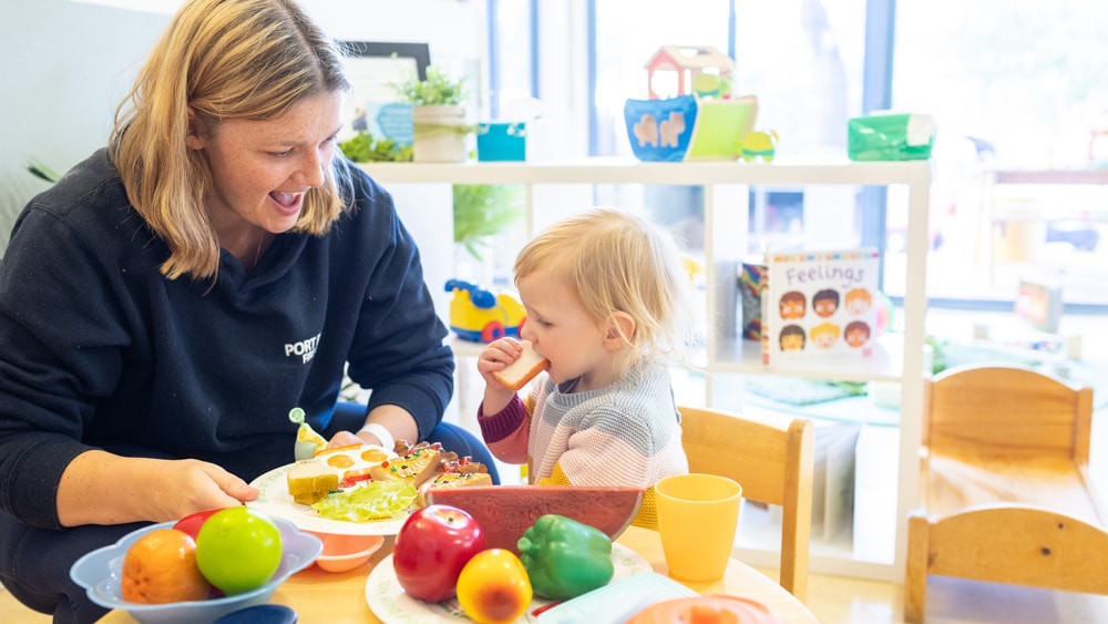 Parent and child playing with toy food in play kitchen in QEC PlayRoom.