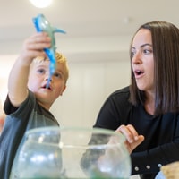 Mum watching child play with toy shark
