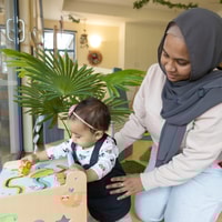 Child playing with toddler in QEC PlayRoom.