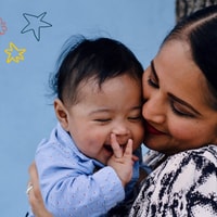 Mum holding baby close and smiling.