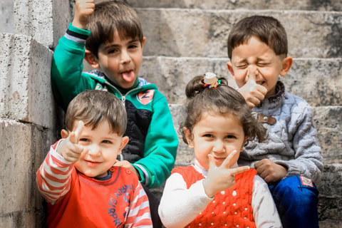 Group of children sitting together on steps, smiling at camera