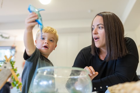 Toddler playing water play with parent