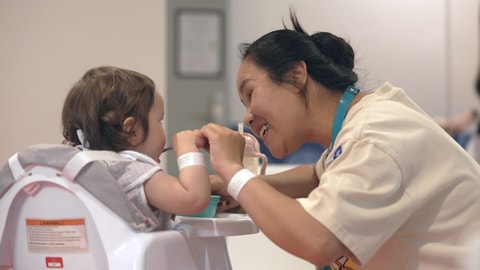 Parent feeding toddler in highchair