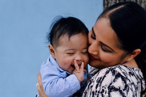 Mum holding baby close and smiling.