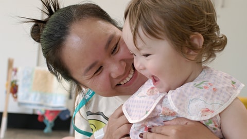 Parent holding and smiling at toddler