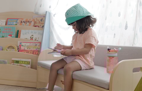 Toddler sitting in playroom reading a book