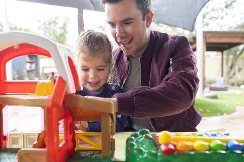 Dad playing outside toys with toddler