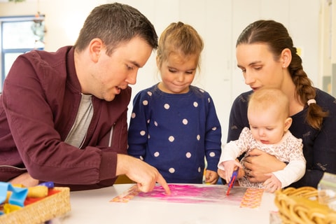 Parents interacting with child and baby in QEC PlayRoom.