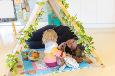 Parent and child playing under tent and interacting, in QEC PlayRoom.