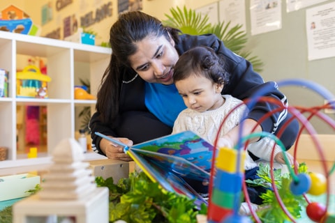 Parent reading book to toddler in QEC PlayRoom.