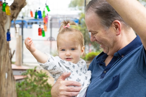 Parent holding toddler and pointing up at tree in QEC sensory garden.