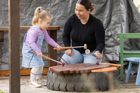 Parent and child playing with instruments in the QEC sensory garden.