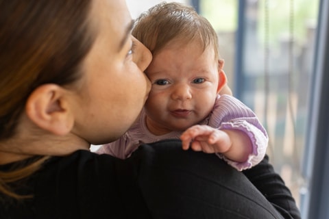 Parent kissing baby on cheek.