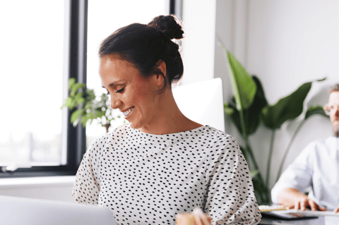 Image of staff member working at desk and smiling.