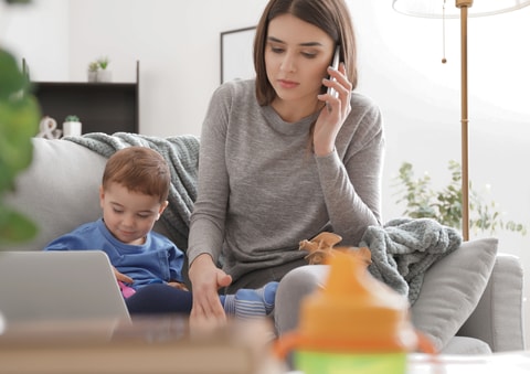 Mum on phone with child sitting next to her